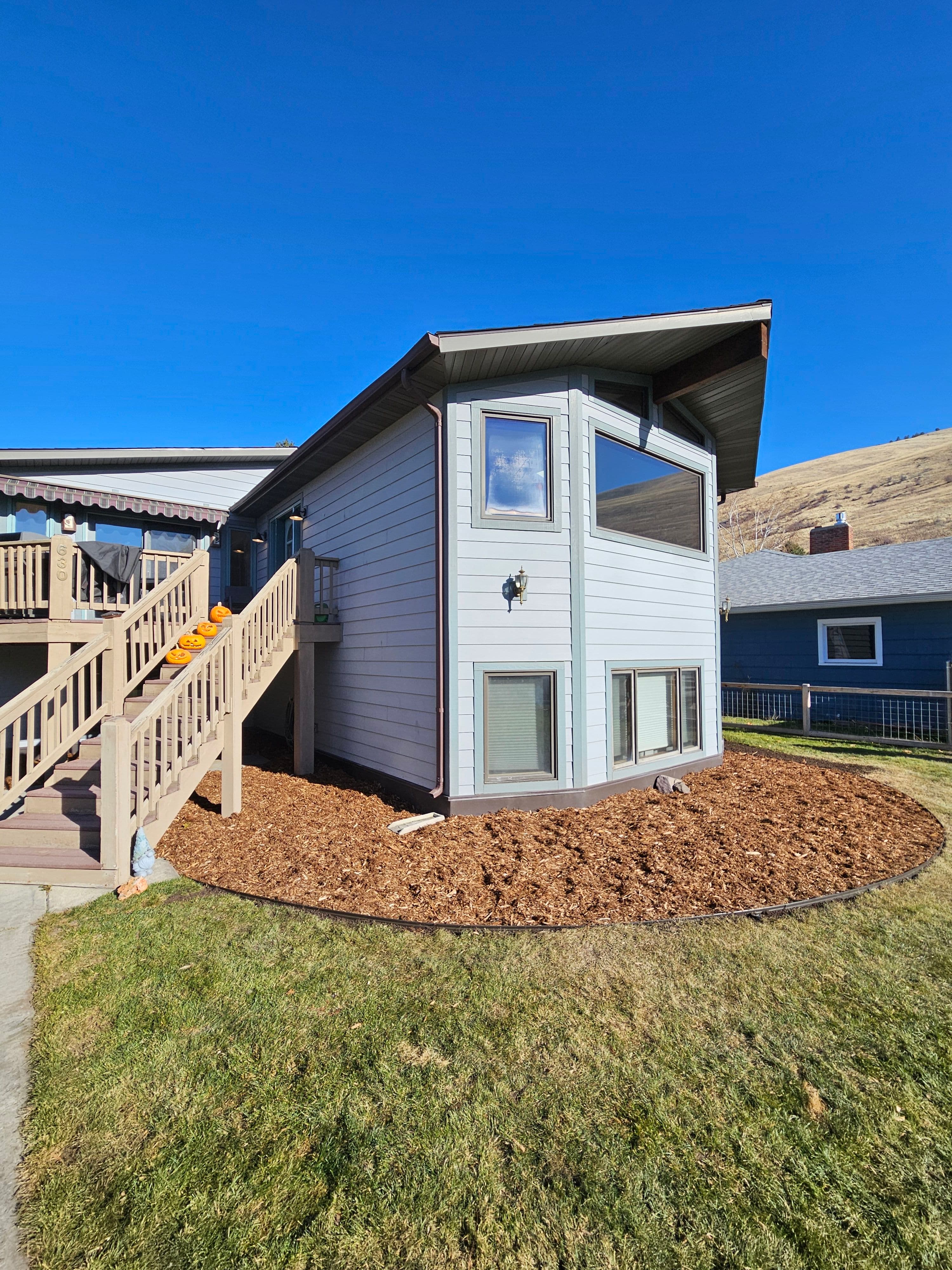 Modern two-story home exterior with landscaped yard and large windows under a blue sky.