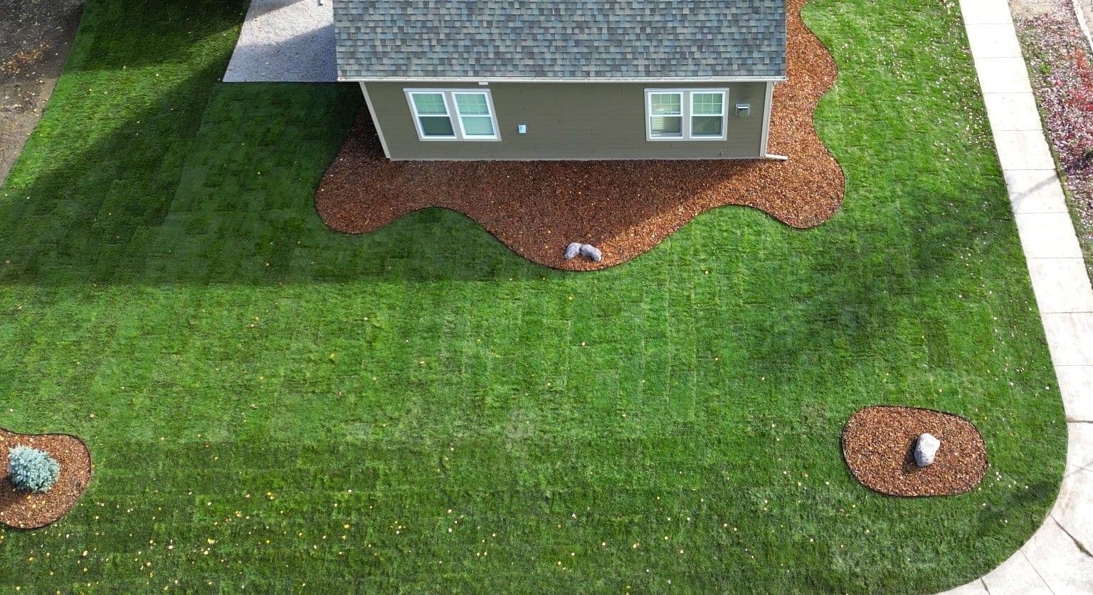 Aerial view of a house with fresh landscaping, mulch beds, and a well-maintained lawn.