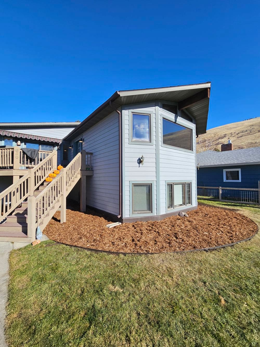 Modern two-story house with landscaped yard and steps leading to entrance, under clear blue sky.