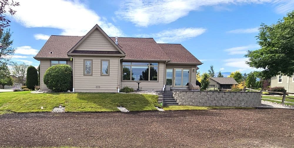 Charming house with large windows, landscaped yard, and clear blue skies. Ideal for family living.