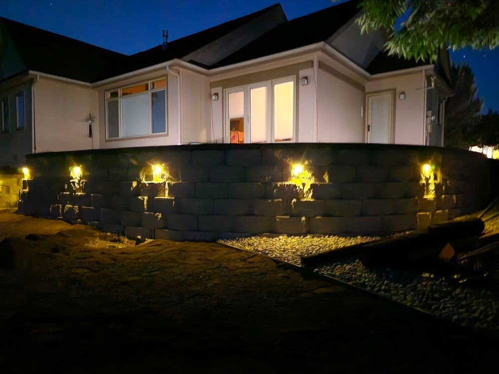 Modern home at night with illuminated retaining wall and pathway lighting.